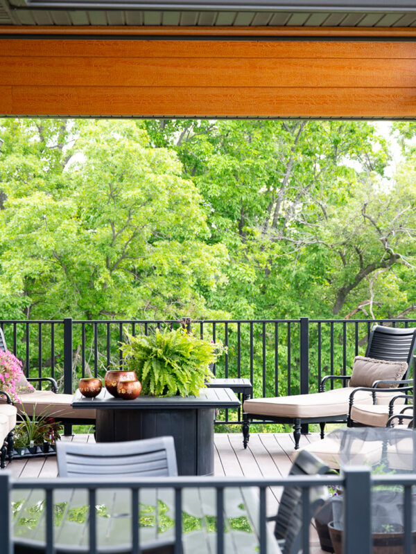 Deck & Porch project example by Custom Pro Homes. A deck decorated with potted flowers, black railings, and accented furniture.